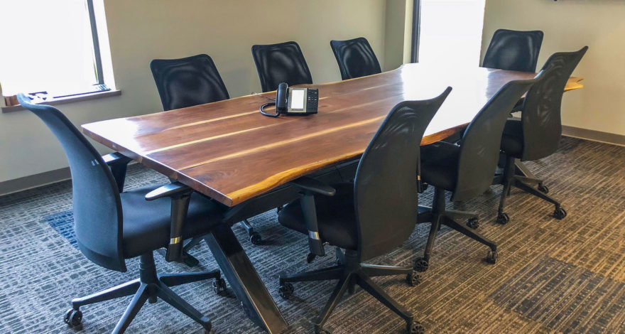 Walnut live-edge custom table top with steel table base for boardroom of corporate office space.